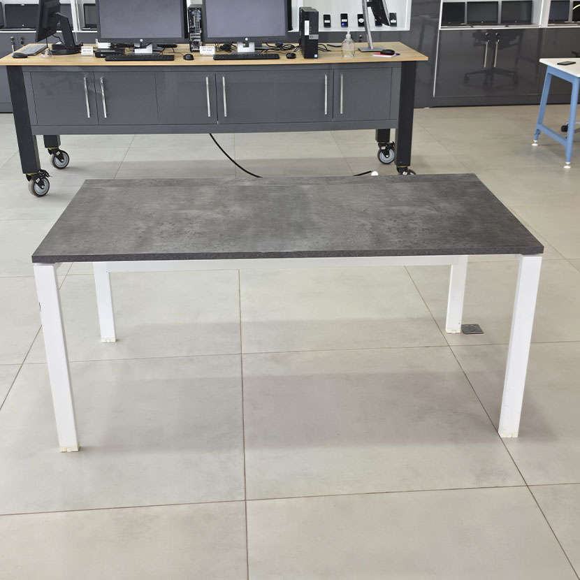 Table de bureau professionnelle avec plateau gris béton, piètement métallique blanc et grande surface de travail.
