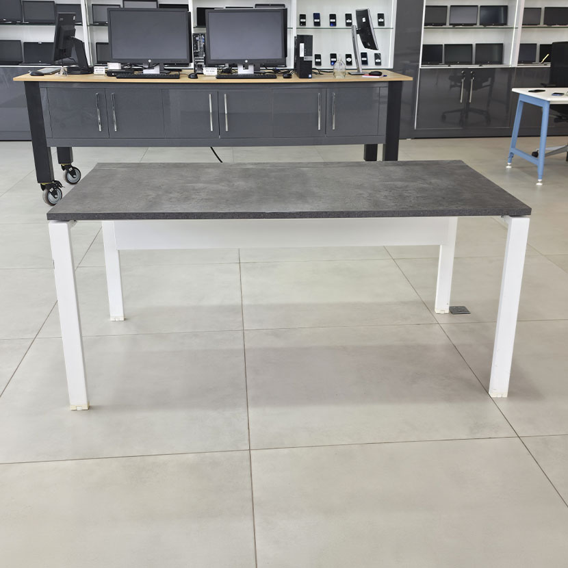 Table de bureau professionnelle avec plateau gris béton, piètement métallique blanc et grande surface de travail.